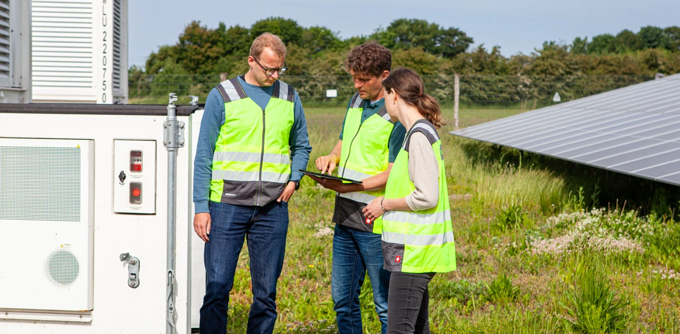 Team im Solarpark beim Speicher